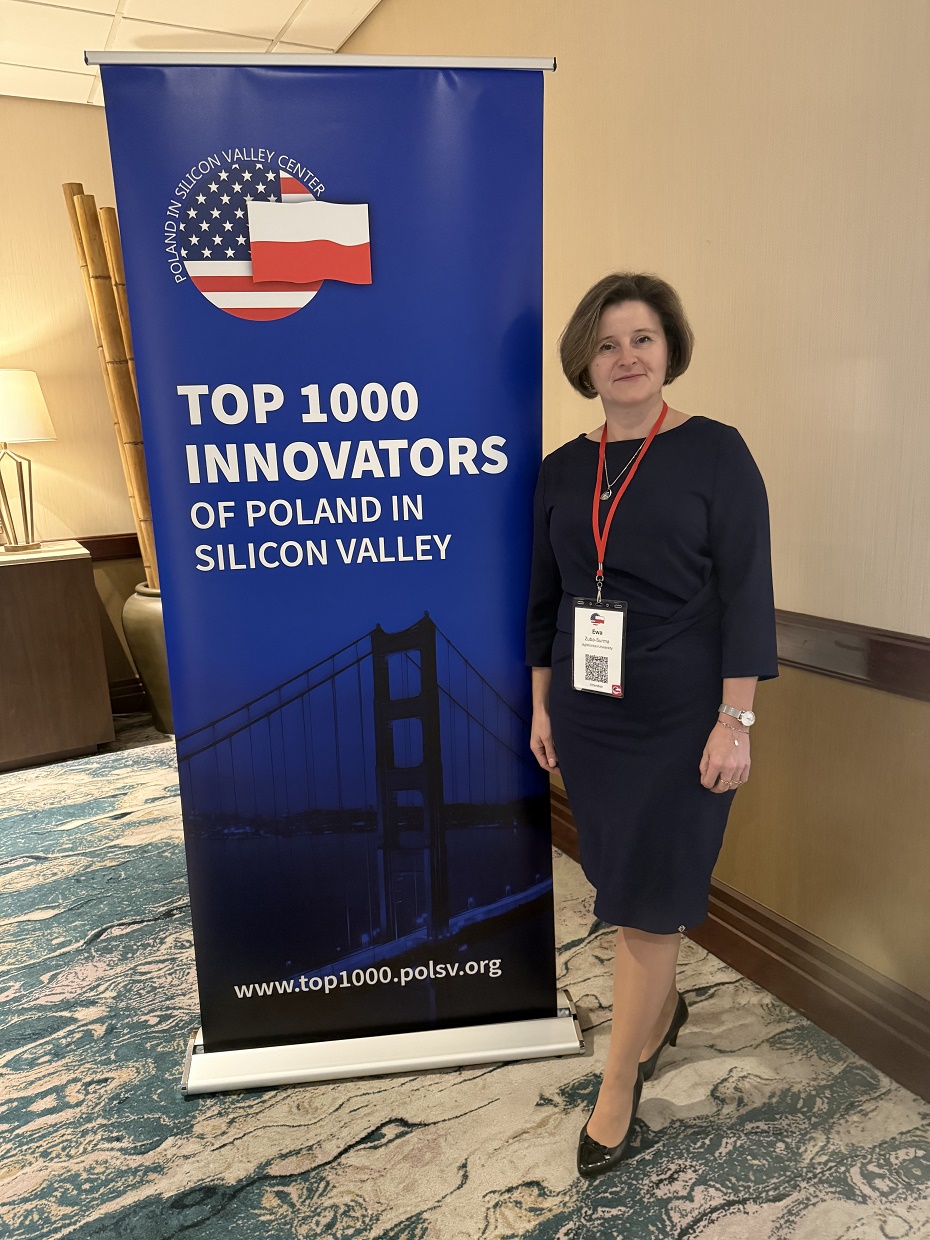 Kobieta stoi koło rollupu z napisem TOP 1000 Innovators